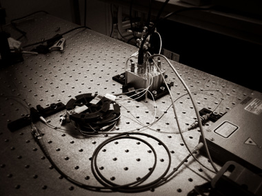 The optical bench inside the ANU Quantum Random Number Generator lab in Canberra, Australia. Black-and-white photograph of the optics array used to measure quantum vacuum fluctuations.